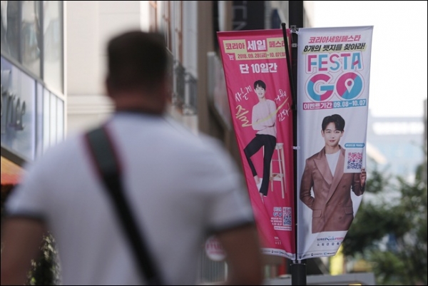 오는 28일부터 다음달 7일까지 10일간 열릴 '코리아 세일 페스타'를 알리는 서울 명동의 홍보물 앞을 한 행인이 걸어가고 있다. / 뉴시스