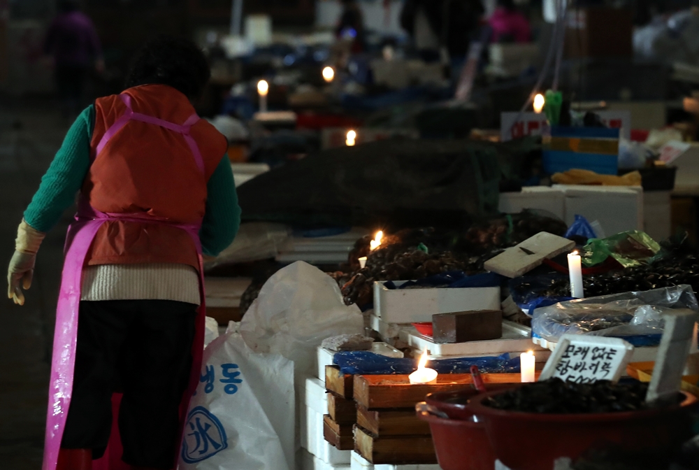 수협이 노량진 수산시장 구시장 전역에 단전과 단수를 진행한지 하루 지난 6일 구시장 상인들이 촛불을 켜고 장사를 하고 있다. /뉴시스