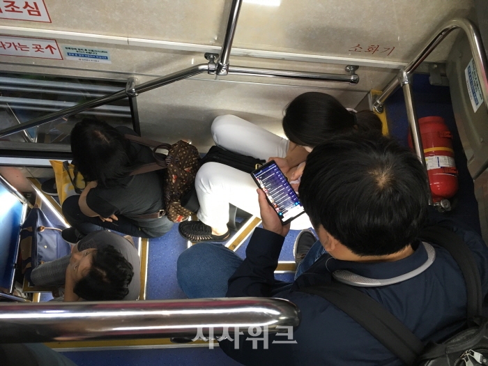 2층버스의 2층으로 올라가는 계단을 승객들이 좌석 삼아 앉아있다./서종규 기자
