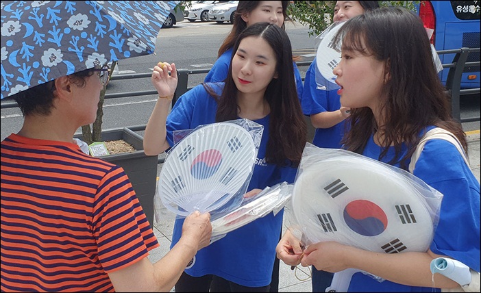 지난 14일 bhc치킨 '해바라기 봉사단' 단원들이 서울 서대문구 독립문 인근에서 시민에게 태극기를 나눠 주며 태극기의 의미를 설명해주고 있다. / bhc