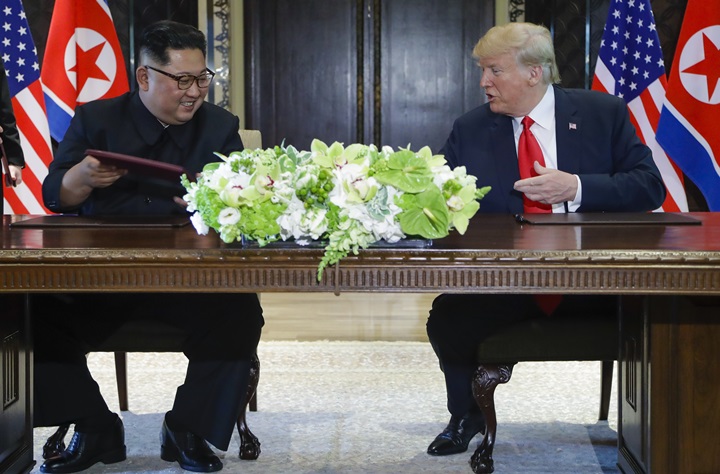 트럼프 대통령과 김정은 위원장이 합의문 서명식을 마치고 악수를 문서를 교환하고 있다. <뉴시스/AP>