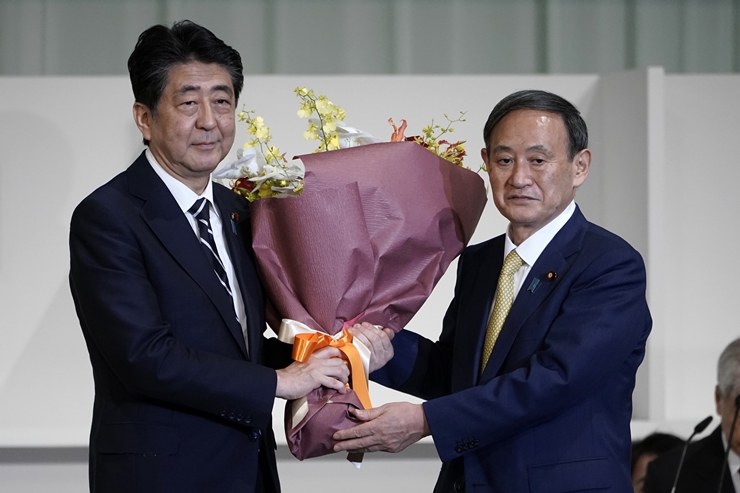 아베 신조(왼쪽) 일본 총리가 14일 도쿄의 한 호텔에서 열린 자민당 총재 선거에서 총재로 선출된 스가 요시히데 관방장관에게 꽃다발을 건네며 축하하고 있다. 스가 관방장관은 이날 열린 총재 선거에서 총재로 선출돼 사실상 새 총리로 확정됐다. /AP-뉴시스