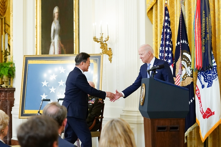 문재인 대통령이 21일 오후(현지시간) 미국 워싱턴 백악관 이스트룸에서 열린 한국전쟁 명예 훈장 수여식에 참석해 단상에 오르며 조 바이든 미국 대통령과 악수를 하고 있다. /뉴시스