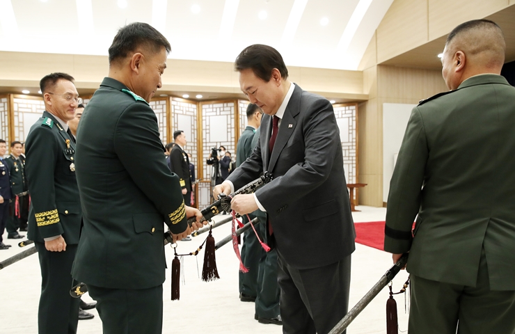 윤석열 대통령이 7일 서울 용산 대통령실 청사에서 열린 장성 보직 신고 및 삼정검 수치 수여식에서 엄용진 육군군수사령관에게 직접 다가가 수치 위치를 조정해주고 있다. /뉴시스