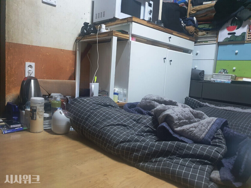 해당 사진은 가족돌봄청년인 수호 씨가 머물고 있는 실제 집의 내부 모습이다.  성인 3명이 다리를 펴고 눕기에도 비좁은 반지하. 수호 씨네 엄마는 매트리스 하나 없이 얇은 이불에 몸을 맡긴다. / 시사위크