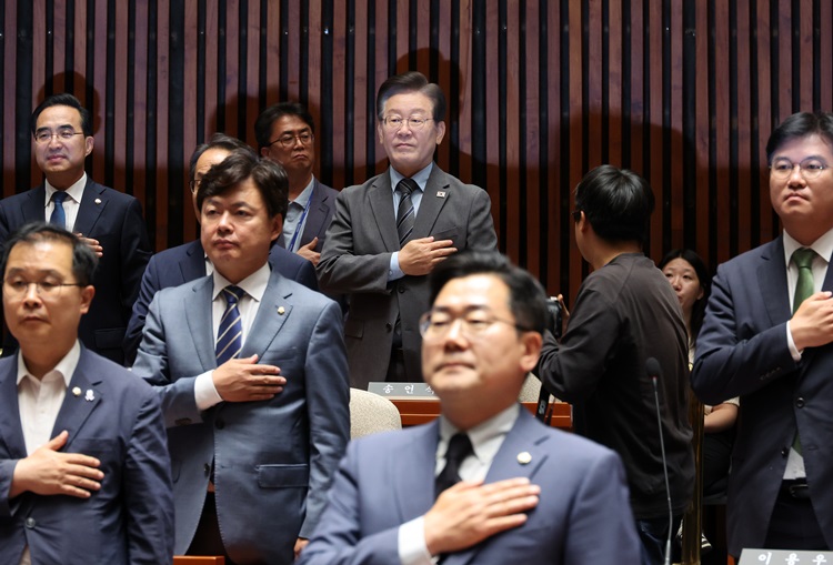 더불어민주당이 오는 8월 18일 서울 올림픽 체조경기장에서 전국당원대회(전당대회)를 개최하기로 결정한 가운데, 당 대표 선출방식과 관련한 ‘전당대회 룰’이 관심사로 떠올랐다. 사진은 이재명(위 가운데) 전 대표가 27일 오후 국회에서 열린 의원총회에서 국기에 대한 경례를 하고 있는 모습. 아래 가운데는 박찬대 당 대표 직무대행 겸 원내대표. / 뉴시스