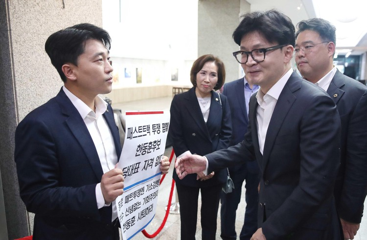 한동훈 국민의힘 당대표 후보가 지난 18일 오후 서울 중구 서울시의회에서 열린 국민의힘 서울시의회 의원간담회 회의장 앞에서 ‘패스트트랙 투쟁 폄훼 한동훈 후보 당대표 자격 없다’가 적힌 피켓을 든 이희원 서울시의원(국민의힘)과 이야기를 나누고 있다.  /뉴시스