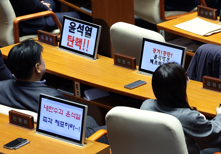 13일 국회에서 열린 제419회 국회(임시회) 제3차 본회의 '윤석열 대통령 위헌적 비상계엄 선포 내란행위 관련 긴급현안질문'에서 민주당 의원들의 모니터에 대통령 탄핵 및 체포를 촉구하는 메시지가 크게 떠 있다. / 뉴시스