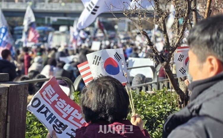 31일 한남동 관저 인근에서 열린 집회에 참가한 한 여성이 '탄핵 반대, 이재명 구속' 문구가 적힌 피켓을 들고 있다.  / 한남동=권신구, 정소현 기자