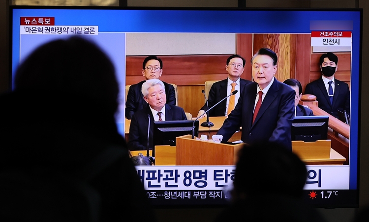 26일 오전 서울 용산구 서울역에서 시민들이 어제 열린 '윤석열 대통령의 탄핵 심판 최종 변론' 관련 뉴스를 시청하고 있다. / 뉴시스