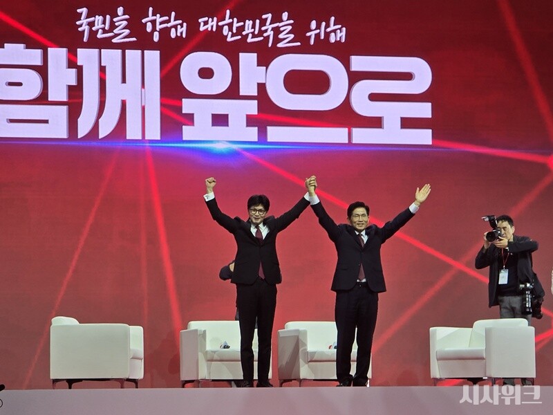 한동훈(좌)·김문수 후보가 무대에 올라 두 손을 번쩍 들어올리고 있다. 두 후보는 투표 결과가 집계되는 동안 무대에 올라 ‘후보자 대담 이벤트’에 참여했다. / 시사위크  