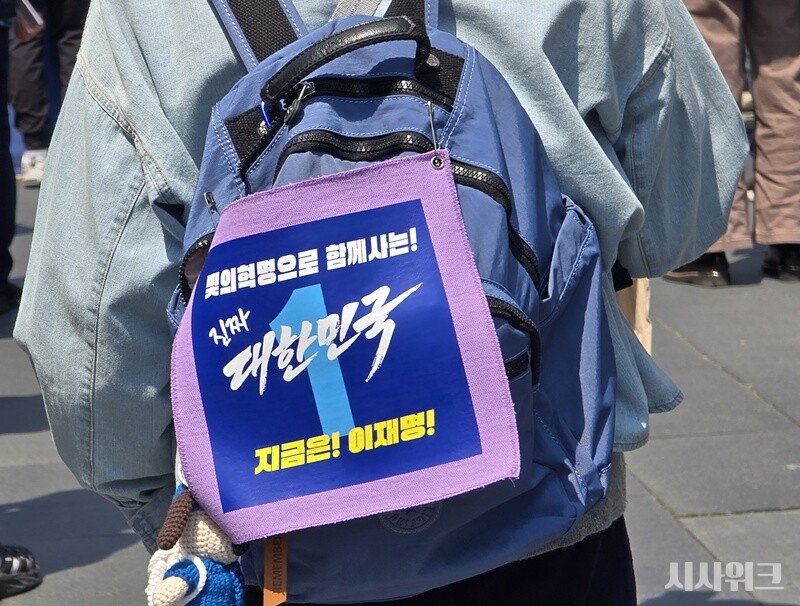 '빛의 혁명으로 함께사는 진짜 대한민국 지금은 이재명'이란 팻말을 가방에 달고 있는 지지자 모습. / 사진=김두완 기자