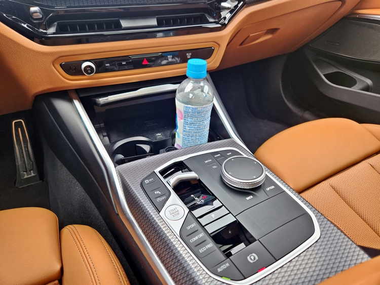 BMW 320i 투어링 1열 주요 조작부. 페트병이 보관된 컵홀더 앞쪽에 스마트폰 무선충전 패드가 위치한다. 가속페달은 오르간 형식으로 설계돼 장시간 운전에도 상대적으로 피로도가 적다. / 제갈민 기자
