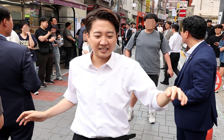 이준석 개혁신당 대선후보가 지난 29일 서울 성북구 고려대 정경대 후문에서 유세를 마치고 인증샷을 찍고 있는 가운데 대학생이(뒤) 이 후보가 TV토론 당시 여성 신체 부위 언급 것 등에 대해 항의를 하고 있다. /뉴시스
