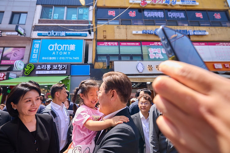 '시사위크'는 시민들에게 '대통령에게 바라는 점'에 대한 의견을 구했다. 사진은 이재명 대통령과 김혜경 여사가 지난 6일 서울 동작구 남성시장을 방문해 한 아이를 안아주고 있는 모습. / 뉴시스