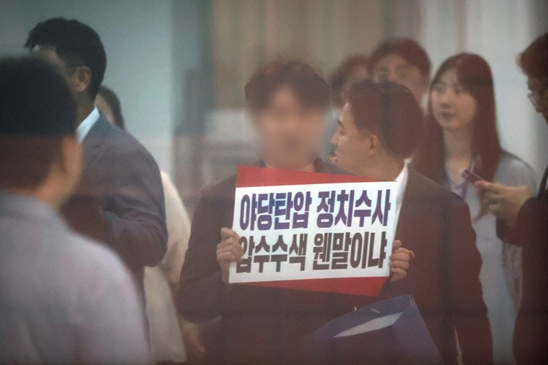 김건희 특검팀이 국민의힘 당사에 대한 압수수색에 나선 13일 서울 여의도 국민의힘 중앙당사에서 당 관계자가 항의 피켓을 들고 있다. / 뉴시스