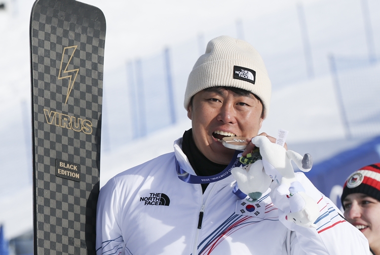 스노보드 은메달리스트 김상겸이 8일(현지 시간) 이탈리아 리비뇨 스노우파크에서 열린 2026 밀라노코르티나 담페초 동계올림픽 스노보드 남자 평행대회전 메달 시상식에서 은메달을 입에다 물고 있다. / 뉴시스
