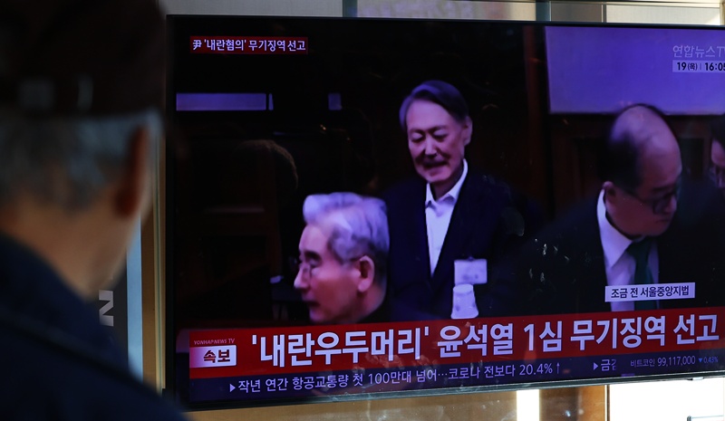 19일 오후 서울 용산구 서울역에서 시민들이 '내란 우두머리 혐의' 윤석열 전 대통령의 1심 선고 공판 중계를 시청하고 있다. / 뉴시스