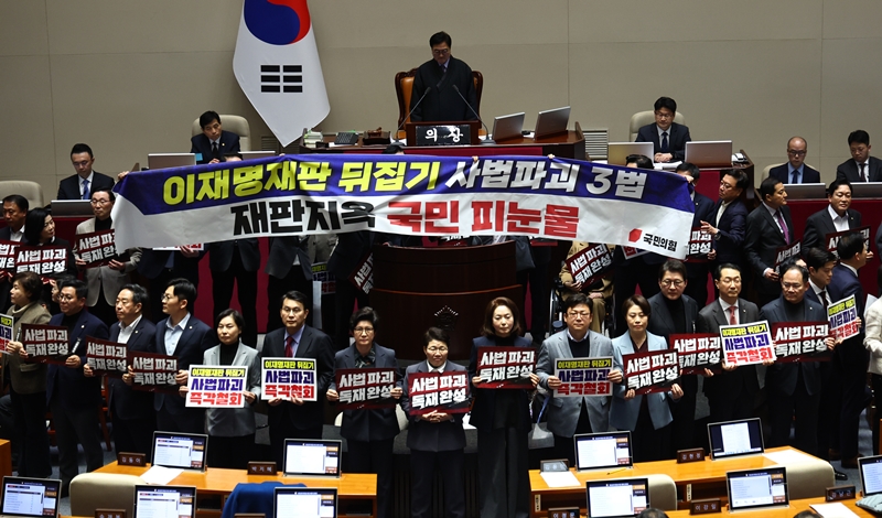 더불어민주당의 사법개혁 3법에 반발한 국민의힘이 3일 장외 투쟁에 돌입한다. 이에 민주당은 “윤어게인을 향한 비겁한 꼬리 흔들기”라며 평가절하에 나섰다. 사진은 국민의힘 의원들이 지난달 27일 국회 본회의에서 헌법재판소법 일부개정법률안(대안)에 대한 무제한 토론 종결동의의 건 투표 도중 '사법개혁 3법 반대' 관련 구호가 적힌 현수막과 피켓을 들고 항의하고 있는 모습. / 뉴시스