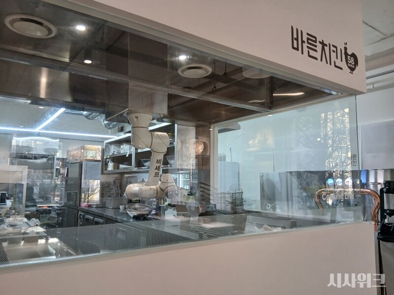 바른치킨은 2022년부터 가맹점 매장에 조리 로봇 도입을 추진해왔다. 사진은 바른치킨 여의도 R점 주방. 통창 너머로 로봇이 움직이는 걸 볼 수 있다. / 사진=김지영 기자