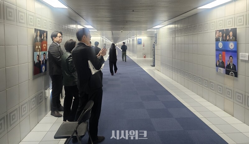 국회 지하통로에 전시돼 있던 윤석열 전 대통령 사진이 3일 철거됐다. 철거된 사진 위치엔 이재명 대통령 사진이 전시됐다. 사진은 국회 관계자들이 지하통로에서 이 대통령으로 교체된 사진을 지켜보고 있는 모습. / 전두성 기자