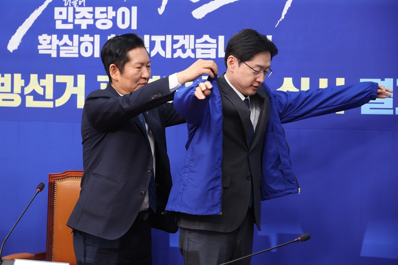 정청래 더불어민주당 대표가 지난 5일 오후 국회에서 열린 중앙당공천관리위원회 공천 심사 발표에서 경남도지사 후보로 확정된 김경수 지방시대위원회 위원장에게 점퍼를 입혀주고 있다. / 뉴시스