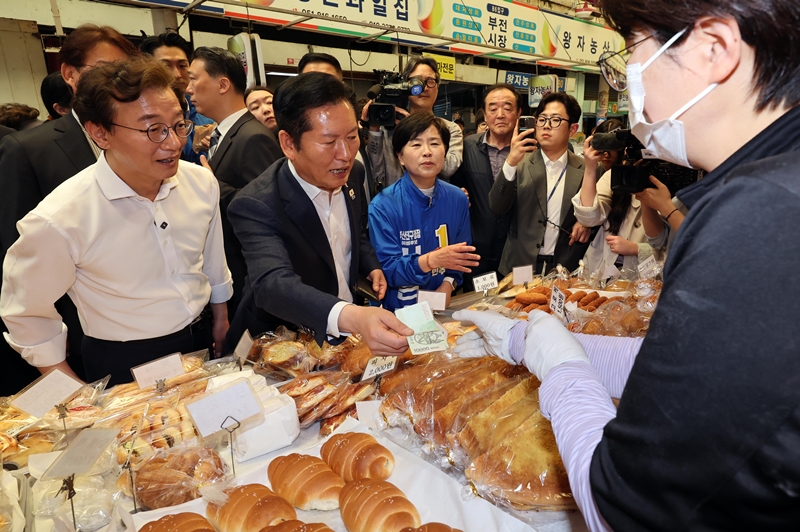 정청래 더불어민주당 대표가 15일 부산 부산진구 부전시장을 방문, 빵을 구입하며 전재수 부산시장 후보 등 6·3 지방선거 후보들의 지지를 호소하고 있다. / 뉴시스