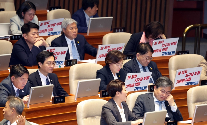 서왕진 조국혁신당 원내대표, 용혜인 기본소득당 대표를 비롯한 개혁진보4당 의원들이 지난 18일 오전 서울 여의도 국회 본회의장에서 '돈 정치 지구당 부활 기득권 야합 규탄한다' 라는 손피켓을 자리에 붙여놓고 있다. / 뉴시스