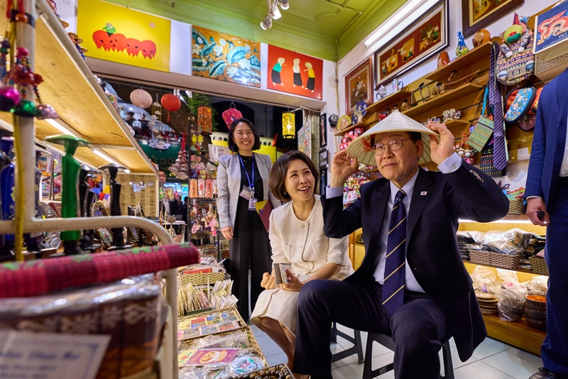 이재명 대통령이 김혜경 여사와 함께 23일(현지시간) 베트남 하노이 시내 한 상점에서 모자를 써보고 있다. / 이재명 대통령 SNS