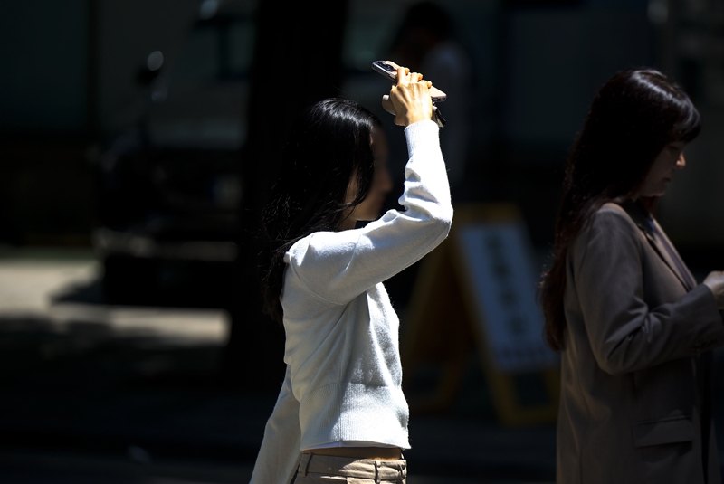 5월부터  30℃를 웃도는 이른 더위가 이어지는 가운데, 역대 가장 이른 시기의 온열질환 사망자가 발생했다. 사진은 서울 중구 시청역 인근에서 한 시민이 손으로 햇빛을 가린 채 이동하는 모습이다. / 뉴시스
