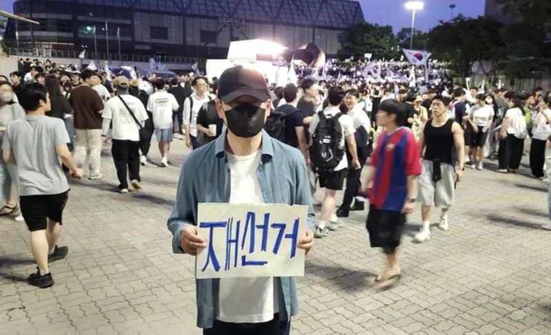 장동혁 국민의힘 대표가 지난 6일 서울 송파구 올림픽공원 핸드볼경기장에 설치된 개표소 앞에서 투표용지 부족 사태에 항의하며 재선거를 요구하는 손피켓을 들고 있다. (사진=장동혁 대표 SNS) / 뉴시스