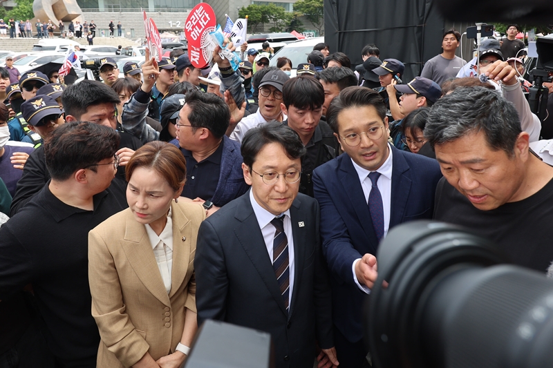천준호, 임오경, 전용기 더불어민주당 의원들이 17일 6·3 지방선거 투표용지 부족 사태에 반발한 시민들이 시위를 이어가고 있는 서울 올림픽공원 핸드볼경기장을 찾아 현장을 둘러보다 시위대의 항의를 받고 발길을 돌리고 있다. / 뉴시스