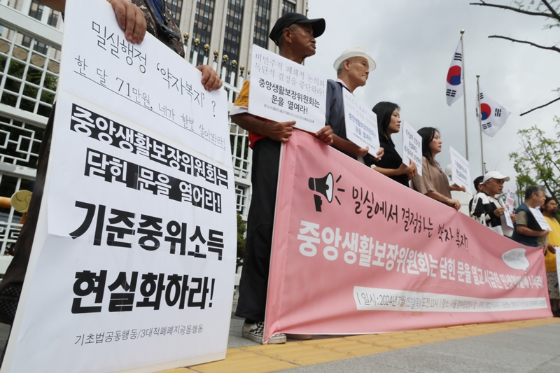시민사회는 중앙생활보장위원회의 새로운 산정방식이 실제 중위소득과의 격차를 해소하기 부족하다며 개선을 요구했다. 사진은 기초법바로세우기 공동행동 등 참석자들이 지난 2024년 서울 종로구 정부서울청사 앞에서 정부 중앙생활보장위원회에 기준중위소득 현실화와 부양의무자 기준 완전 폐지를 요구하는 기자회견을 하는 모습이다. / 뉴시스