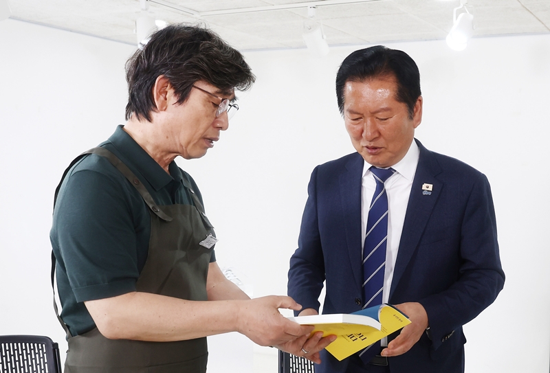 정청래 전 더불어민주당 대표가 지난 6월 24일 오후 서울 성동구 언더스탠드에비뉴에 마련된 청각장애인 수제화 브랜드 '아지오' 매장 오픈 행사에 참석해 유시민 작가로부터 '사랑이 있으니 살아집디다' 책을 전달 받고 있다. (공동취재) / 뉴시스